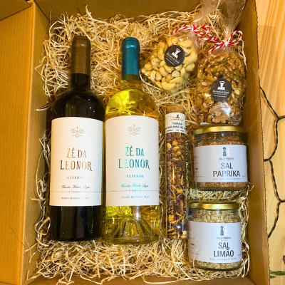Conjunto de vinho, frutos secos, tisana e sal aromatizado numa caixa de cartão com palha decorativa.