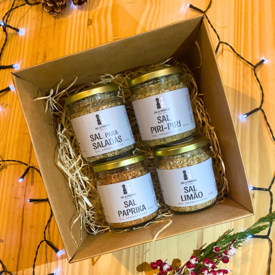 Conjunto de quatro frascos de sal aromatizado em caixa de cartão sobre mesa de madeira