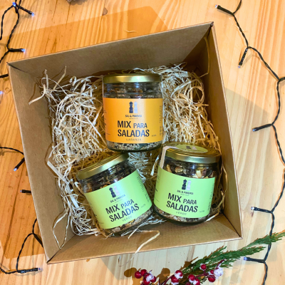 Caixa com três frascos de mix para saladas em embalagens de vidro com rótulos verdes e laranja