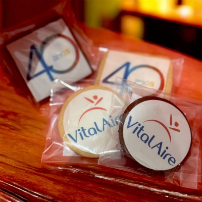 Bolachas embaladas individualmente com logotipos 'Vital Aire' e '40 años' sobre mesa de madeira.