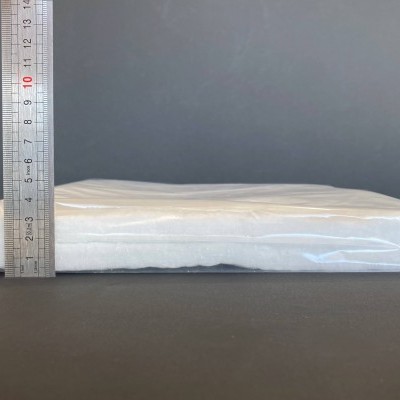 Pacote retangular branco embalado em plástico transparente ao lado de régua metálica