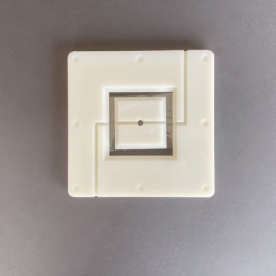 Moldes quadrados brancos com design em camadas e orifício ao centro sobre superfície cinza