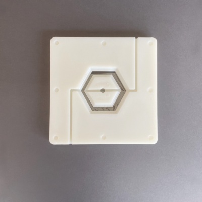 Objeto branco quadrado com recorte hexagonal no centro