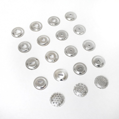 Peças metálicas prateadas circulares e perfuradas sobre fundo branco.