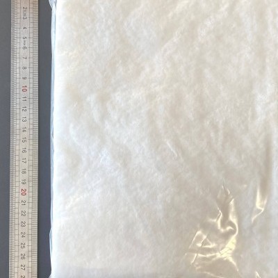 Pacote de material branco felpudo ao lado de régua metálica