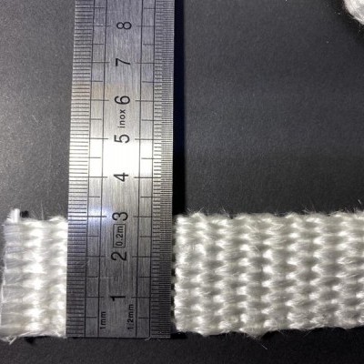 Fitas brancas trançadas ao lado de régua metálica sobre fundo preto