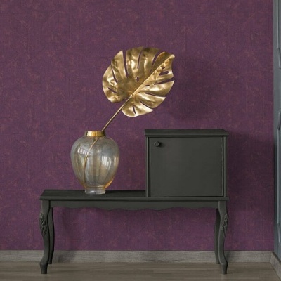 Aparador preto com vaso transparente e folha dourada em parede roxa.