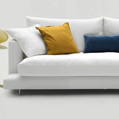 Sofá branco com almofadas coloridas e planta verde ao lado