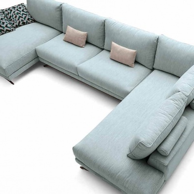 Sofá em forma de U azul claro com almofadas cor de rosa e geométricas