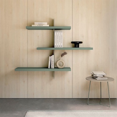 Prateleiras flutuantes verdes com livros e objetos decorativos numa parede clara, com mesa redonda cinza ao lado