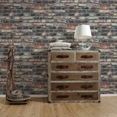 Cómoda de madeira antiga com lâmpada branca, almofada e objeto decorativo de madeira contra parede de tijolos expostos.