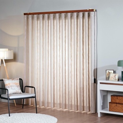 Cortina bege translúcida num ambiente de sala com cadeira e mesa decorativa