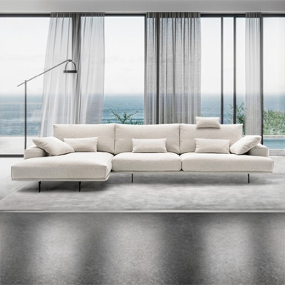 Sofá modular bege claro com almofadas em sala moderna com janelas grandes e vista para o mar