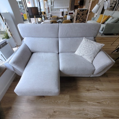 Sofá chaise longue cinza claro com almofada decorativa em loja