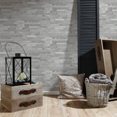 Conjunto decorativo com caixa de madeira, lanterna, almofada, cesta de vime e caixas junto à parede azulejada cinza