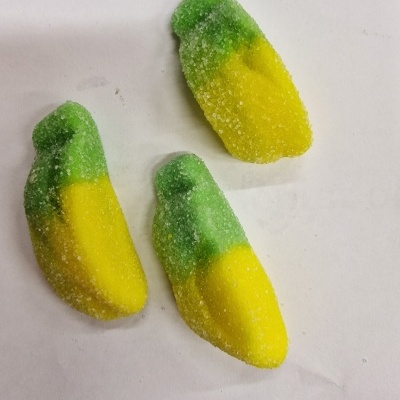 Três gomas verdes e amarelas em forma de dedo cobertas de açúcar