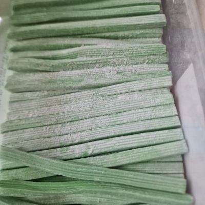 Palitos de pasta verde com pó branco dentro de recipiente transparente