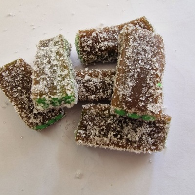 Pedaços de doce com açúcar cristal, verde e castanho, sobre fundo branco