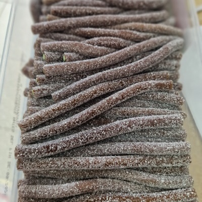 Tiras de doce castanho escuro cobertas de açúcar em recipiente transparente