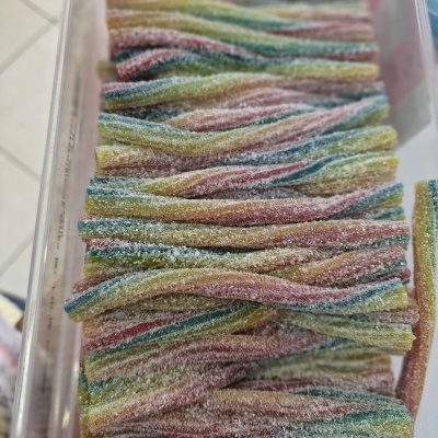 Doces coloridos em tiras cobertas de açúcar numa caixa transparente