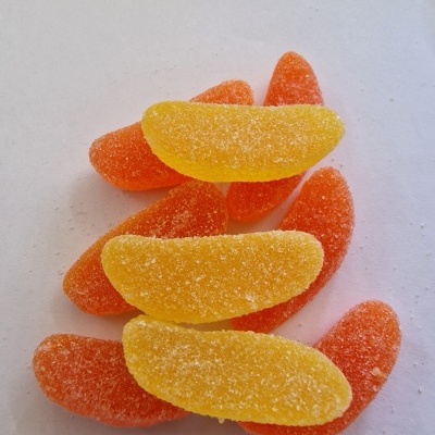 Gomas açucaradas em forma de gomos de fruta laranja e amarelo