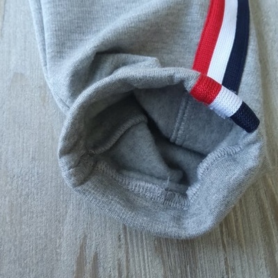 Manguito de roupa cinzenta com faixa vermelha, branca e azul