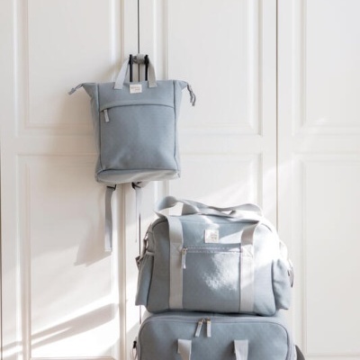 Conjunto de três malas cinzentas empilhadas e penduradas numa porta branca.