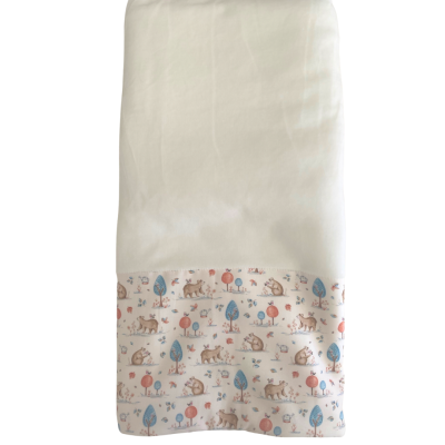 Fralda branca com padrão colorido de animais e árvores na parte inferior