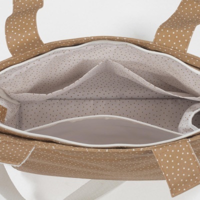 Interior de bolsa castanha com pontos brancos e forro bege com padrão de pontos.
