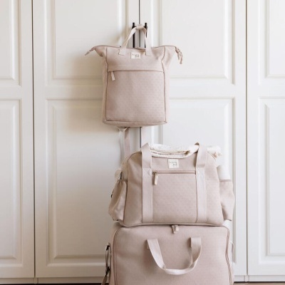 Três malas bege empilhadas em fundo branco