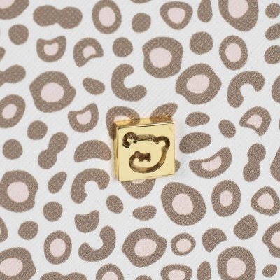 Produto com padrão animal em tons bege e detalhe metálico dourado com desenho de urso