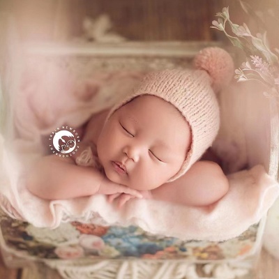 Bebé a dormir com gorro rosa numa caixa forrada com tecido rosa