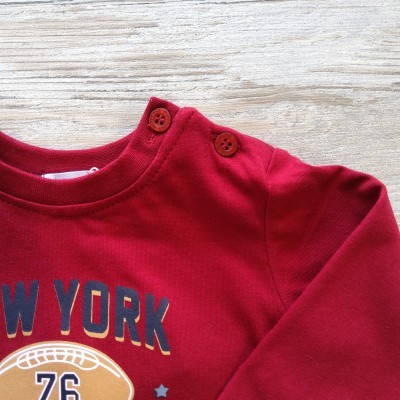 Camisola vermelha para criança com botões no ombro e estampado de futebol americano