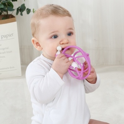 Bebé com brinquedo de silicone roxo num ambiente interior claro