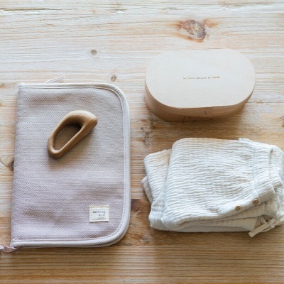 Pasta de tecido bege, mordedor de madeira, caixa oval de madeira, peça de roupa infantil branca