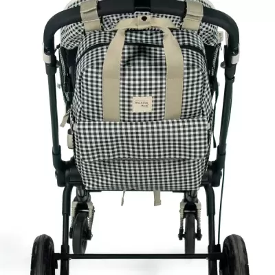 Carrinho de bebé padrão quadrícula preto e branco com alças bege e estrutura preta.