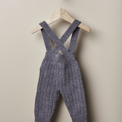 Calças de malha cinzenta com alças penduradas num cabide de madeira