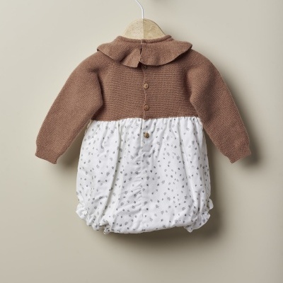 Macacão bebé castanho e branco com padrão floral, pendurado num cabide de madeira