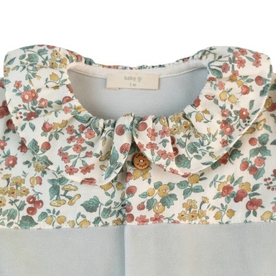 Gola arredondada floral em roupa de bebé azul claro com botão castanho