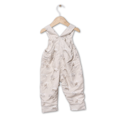 Jardineiras de criança bege com padrão de animais penduradas num cabide de madeira