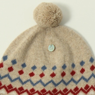 Gorro bege com pompom e padrão geométrico vermelho e azul