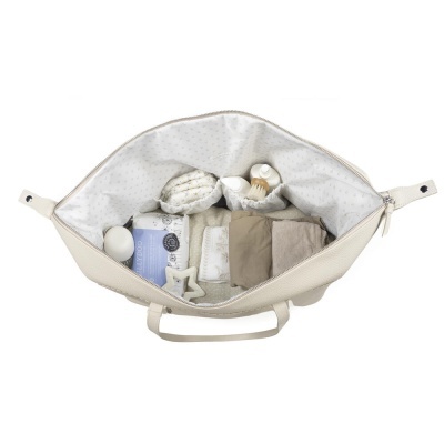 Saco claro aberto com toalhas, sabonete azul e esponjas em tons neutros