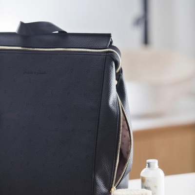 Mala preta em pele sintética com fecho em zíper dourado parcialmente aberta com acessórios de higiene