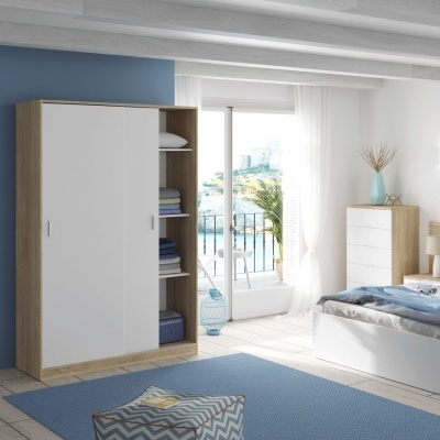 Quarto moderno com roupeiro de madeira clara e branco, cama branca, cómoda, tapete azul e puff geométrico