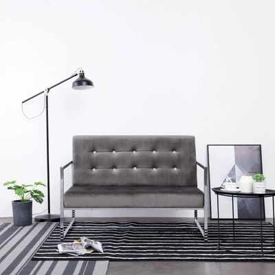 Sofá cinza escuro com estrutura metálica, tapete às riscas, mesa lateral preta, planta decorativa e candeeiro