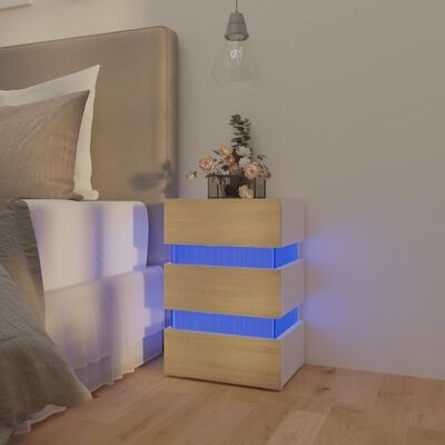 Mesa de cabeceira em madeira clara com iluminação azul ao lado de cama com cabeceira cinzenta