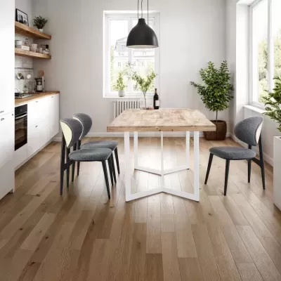 Mesa de jantar de madeira clara com cadeiras cinza numa cozinha moderna com piso de madeira e plantas.