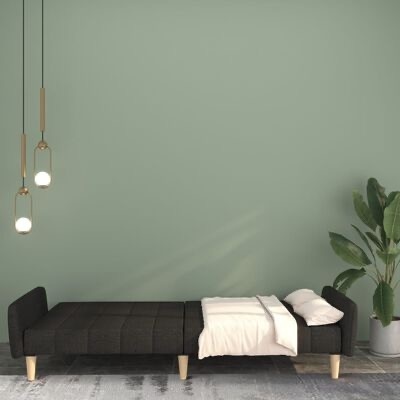 Sofá-cama preto estendido com roupa branca, candeeiros pendentes e planta em vaso