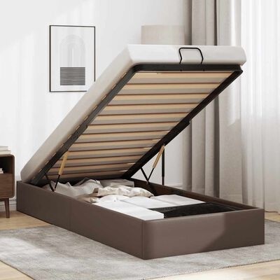 Cama de arrumação castanha com mecanismo elevatório aberta, mostrando espaço interior com roupa, em quarto iluminado