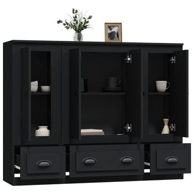 Móvel preto com portas e gavetas abertas mostrando chávenas e jarros com jarra de flores e moldura em cima